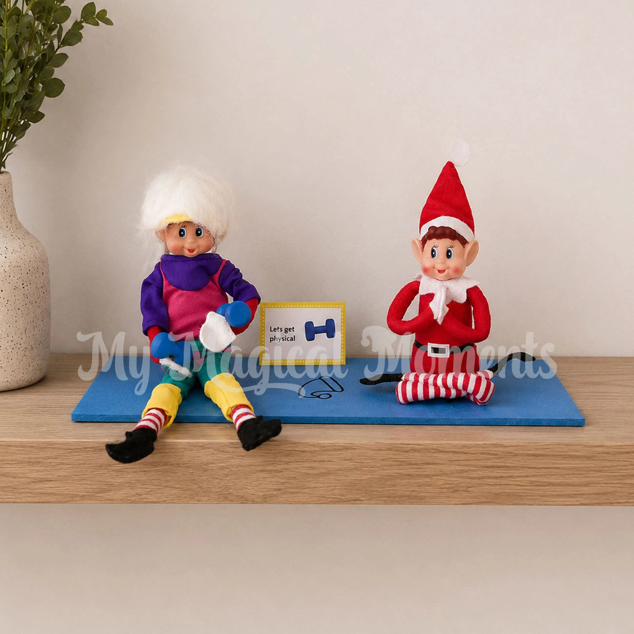 elf wearing a workout costume with mini dumbbells on a yoga matt with an elf doing yoga