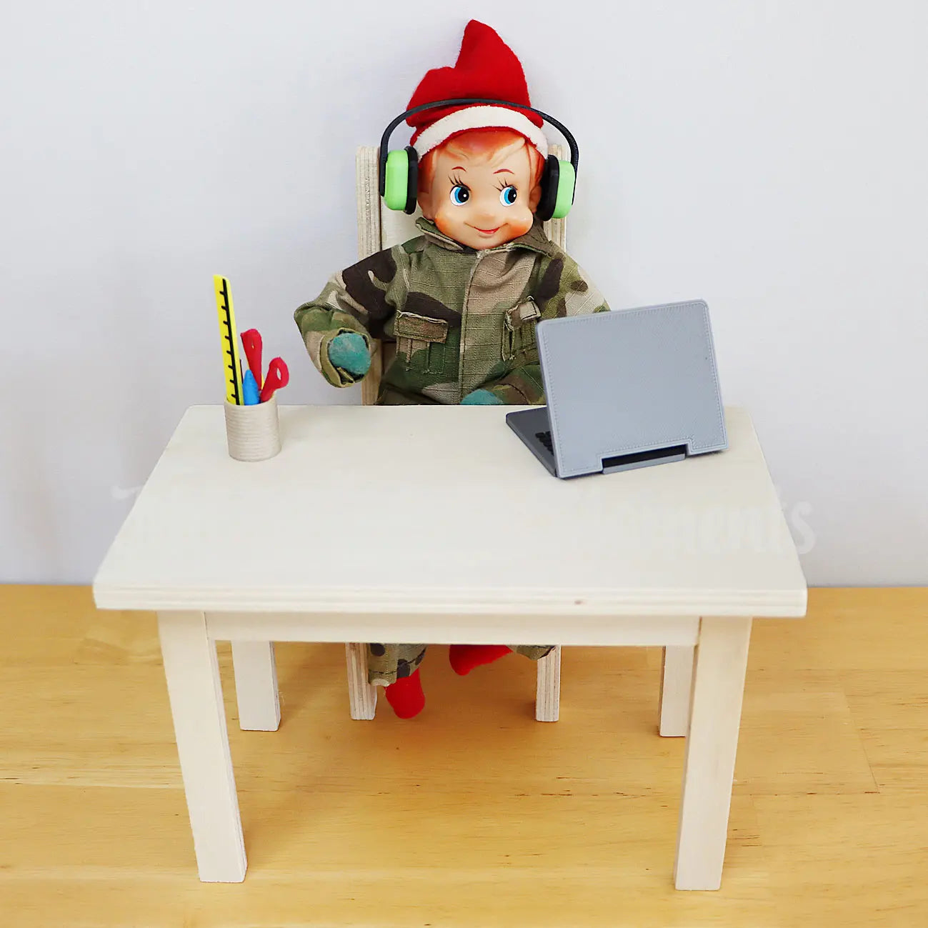 Elf wearing headphones dressed in an army uniform working on a laptop on a mini table