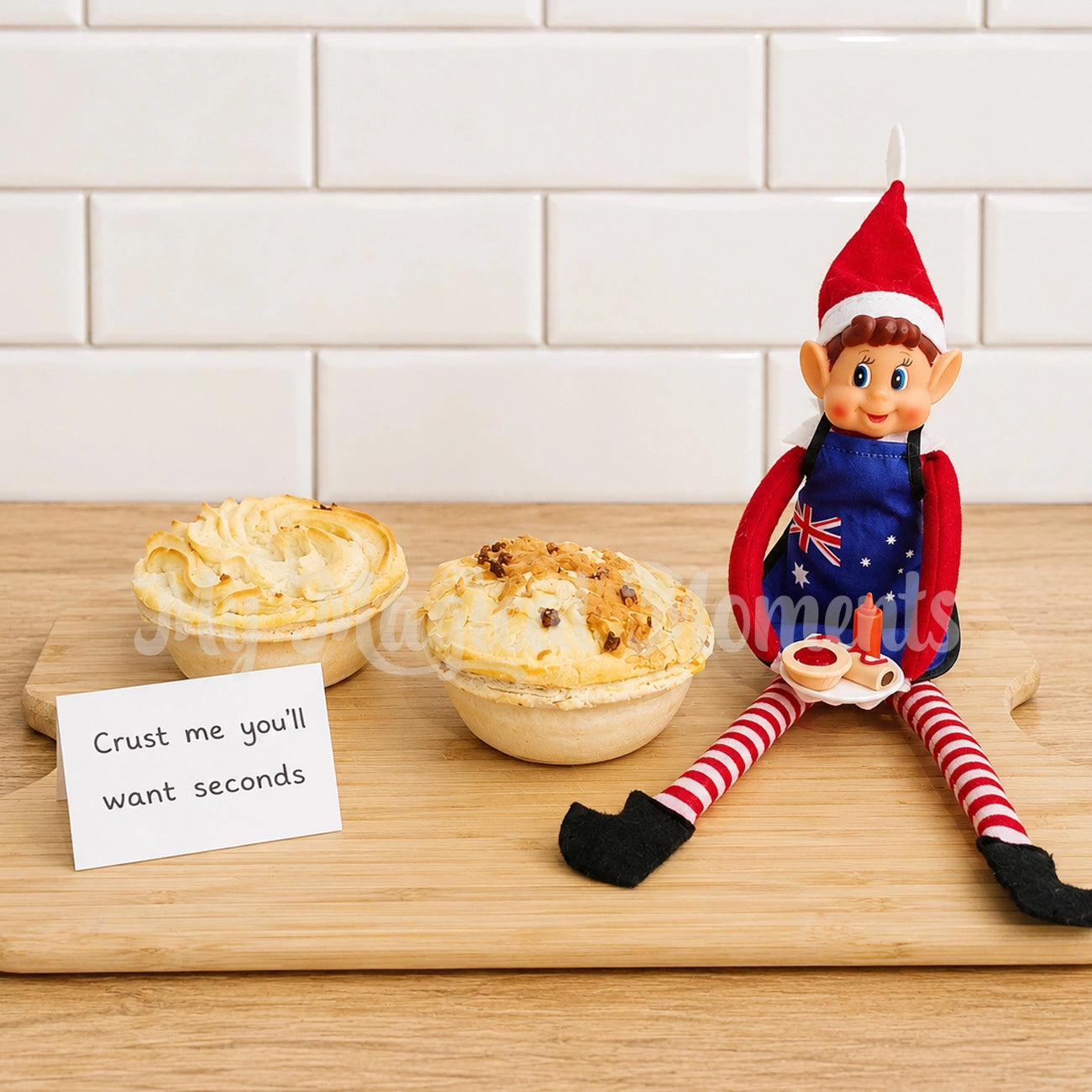 Elf wearing a bbq apron holding miniature pies and sausage rolls on a plate with tiny sauce bottles. Next to real pies and a sign saying crust me you'll want seconds