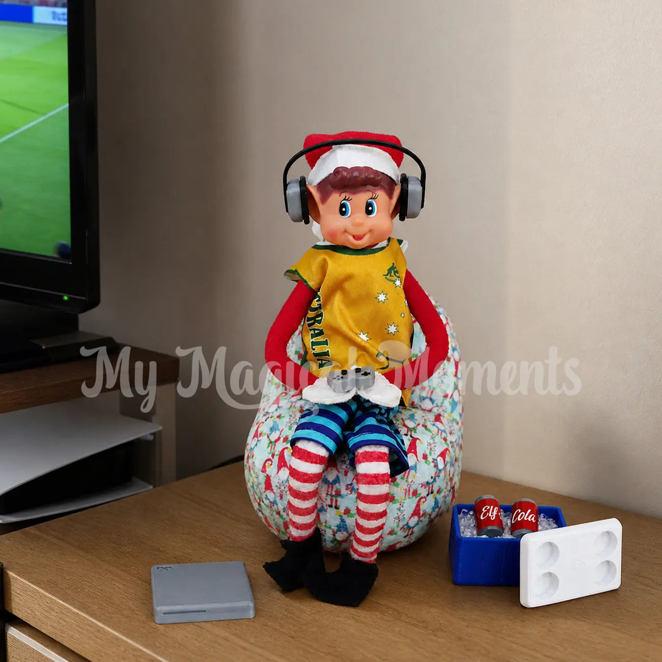 Elf wearing headphones playing a mini gaming set wearing an aussie singlet on a bean bag. With a mini esky filled with cola