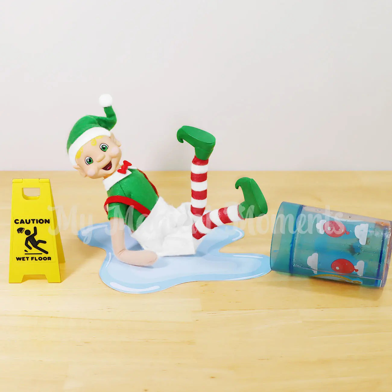 Elf slipping on a puddle of water with a caution wet floor sign