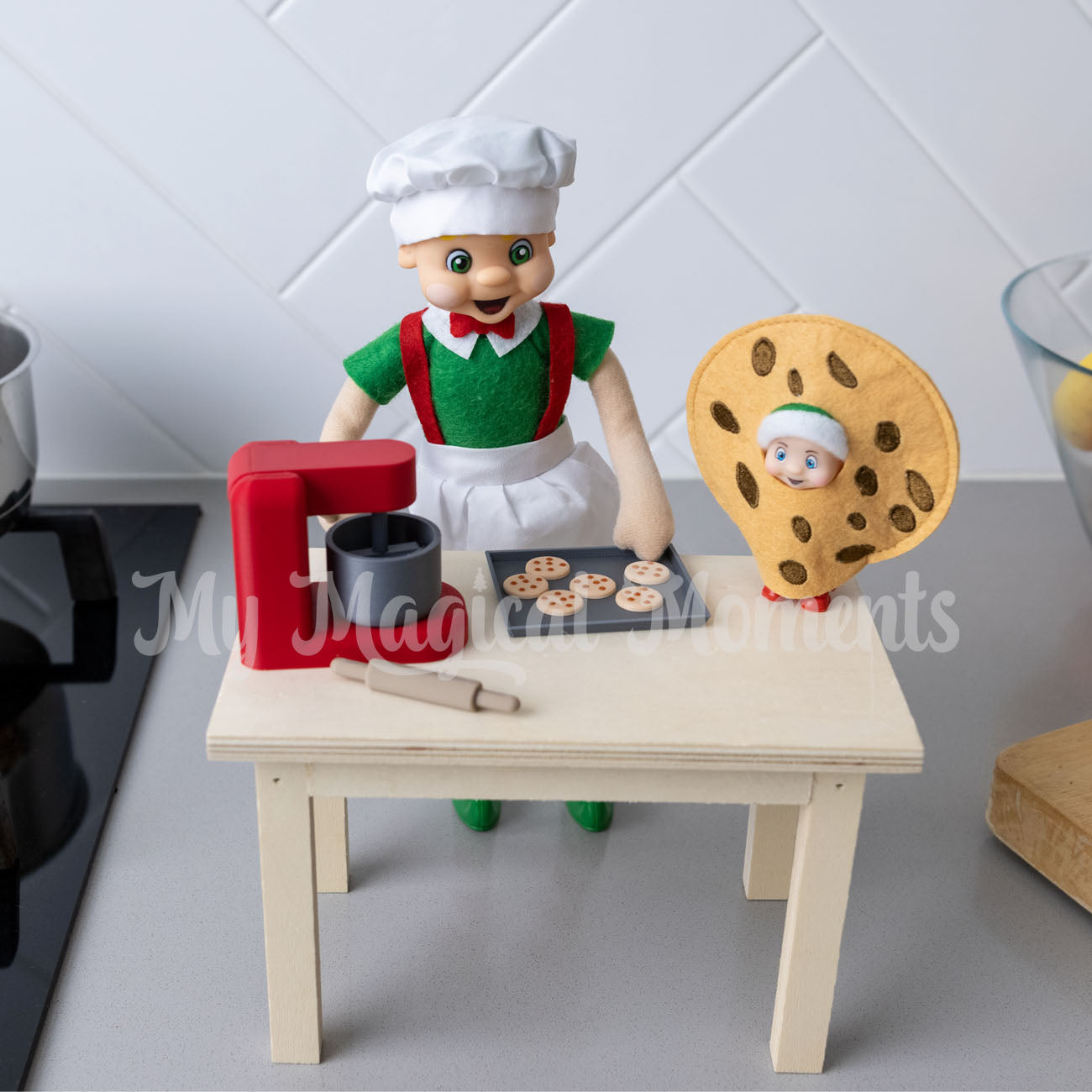 elf wearing a chef costume, cooking with a mini baking set and baby elf wearing a cookie costume