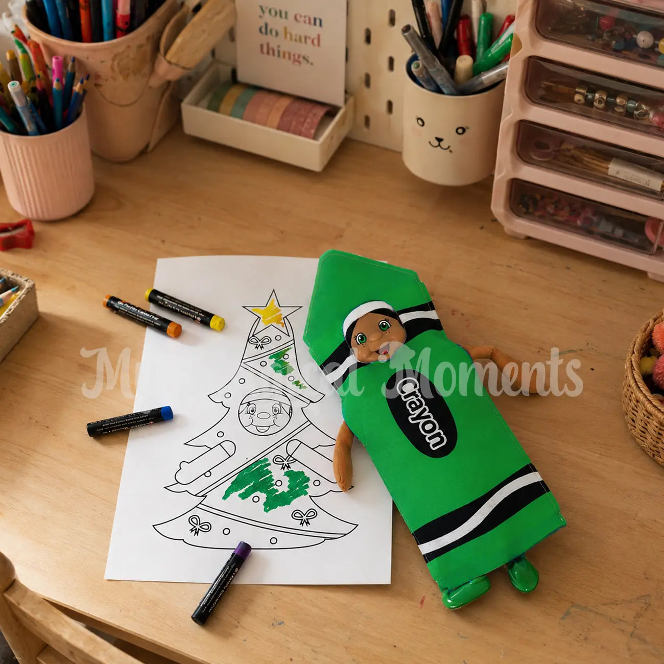 Black hair elf dressed as a green crayon colouring her self with crayons