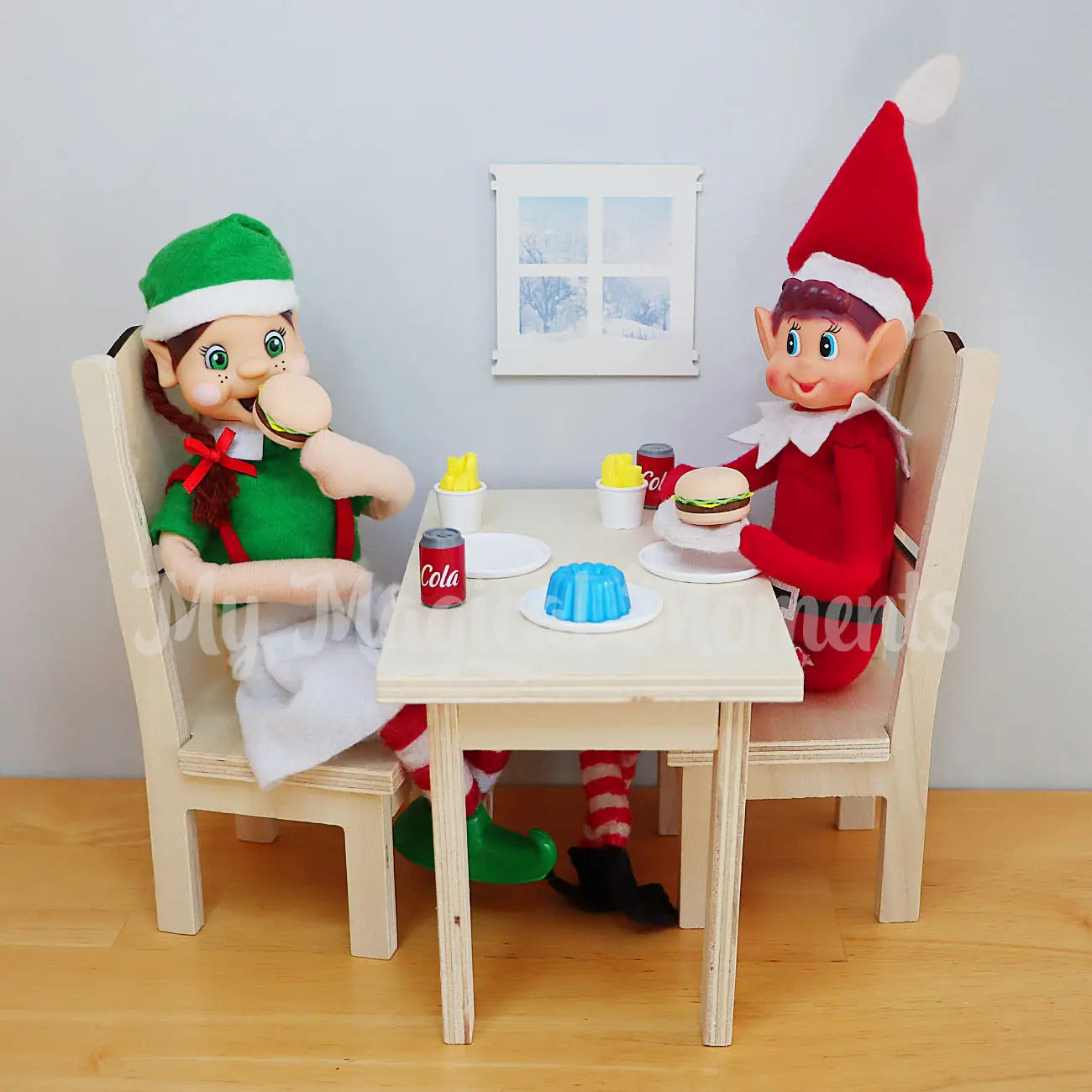 elves dining together on a miniature table and chair, with mini burgers, jelly and cola cans