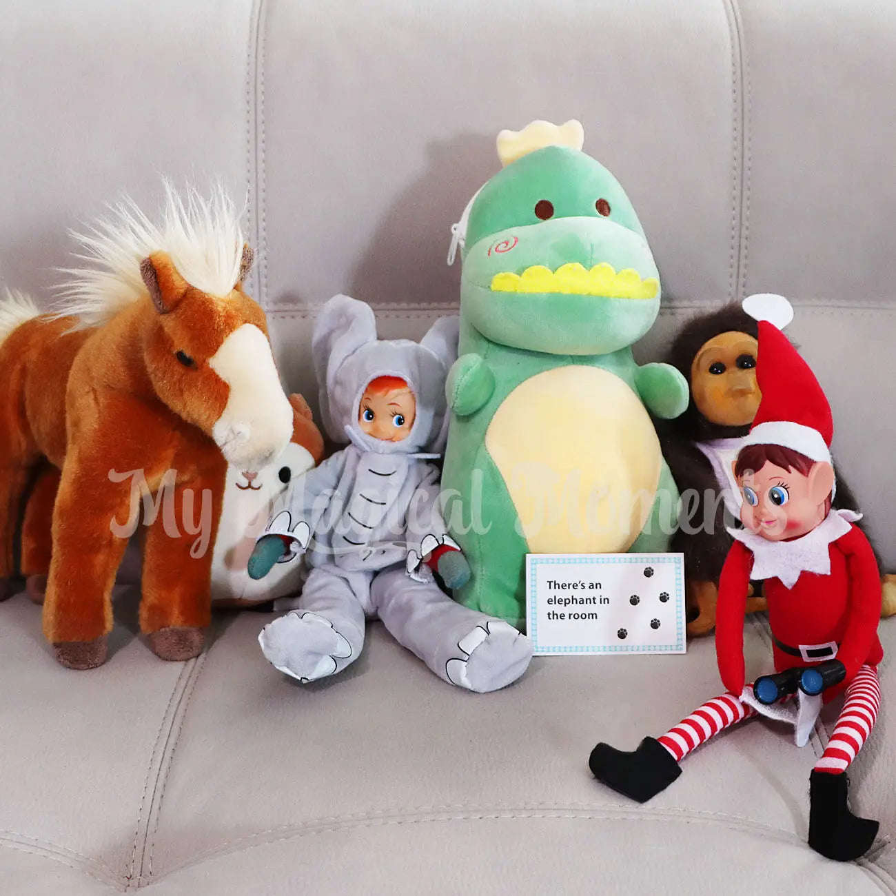 Collection of plush toys including a horse, elephant costume worn by an elf, dragon, and elf on a couch holding mini binoculars