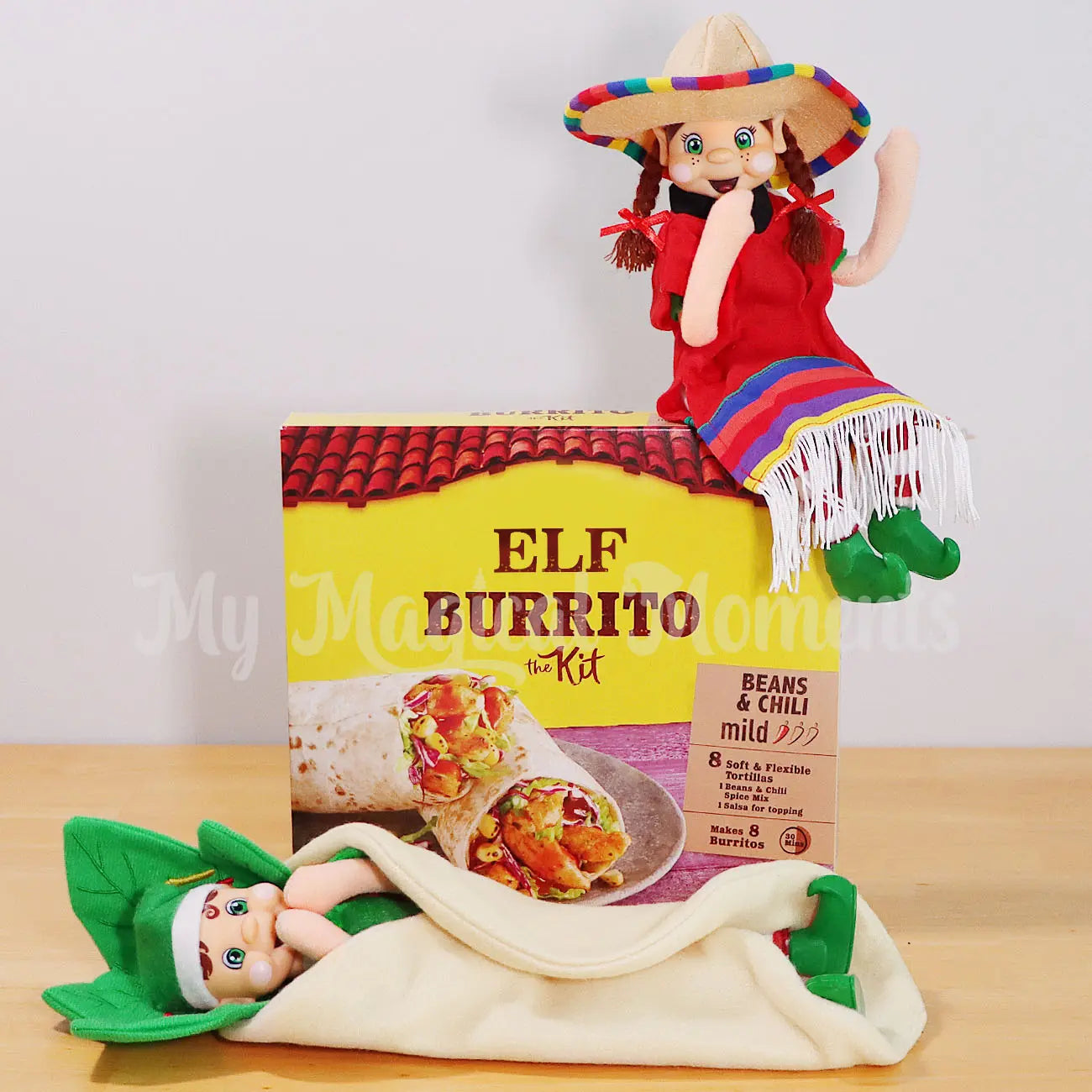 Elf wearing a Mexican outfit sitting on a elf paso burrito kit with an elf dressed as a burrito