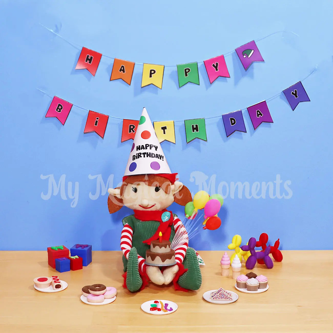 Elf For Christmas holding a mini chocolate Birthday Cake, with elf sized party food, Fairy bread, cupcakes, donuts, pie, sausage rolls soft serves, presents and balloon animals