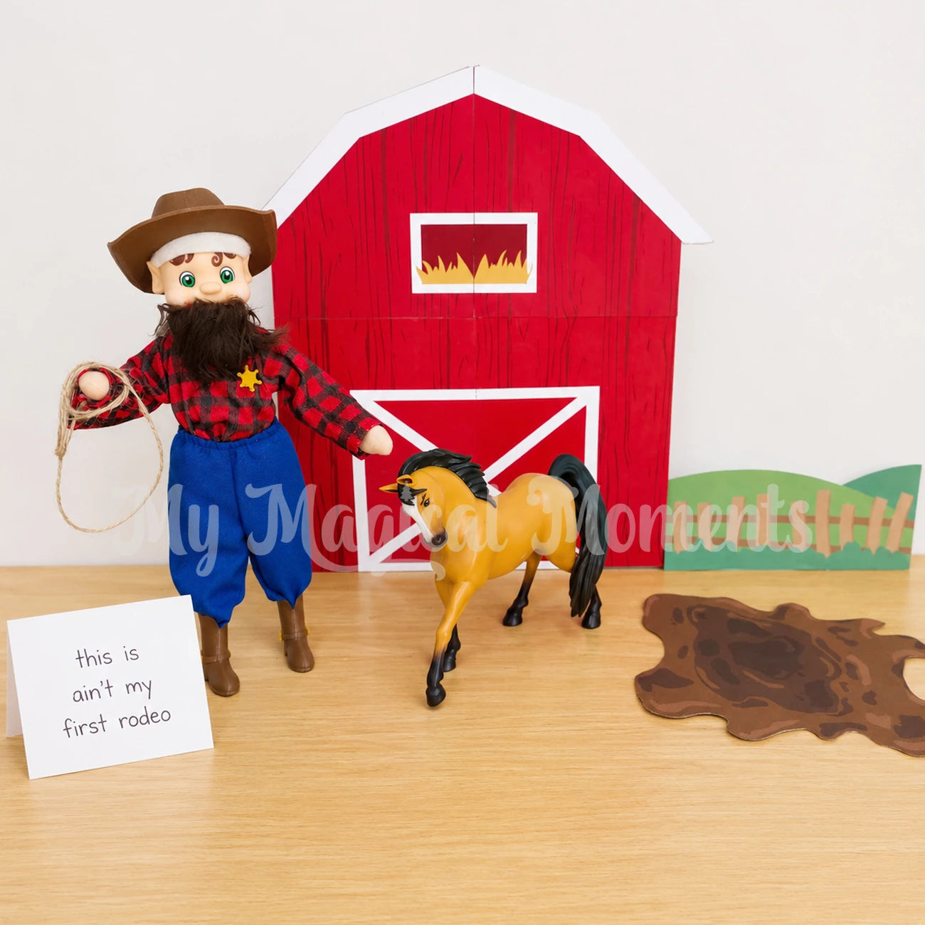 Elf wearing a cowboy hat, cowboy boots, a sherrif badge, blue pants, flannel shirt and beard. With a horse in front of Printable barn, grass and mud splat. There is a sign that says this ain't my first rodeo