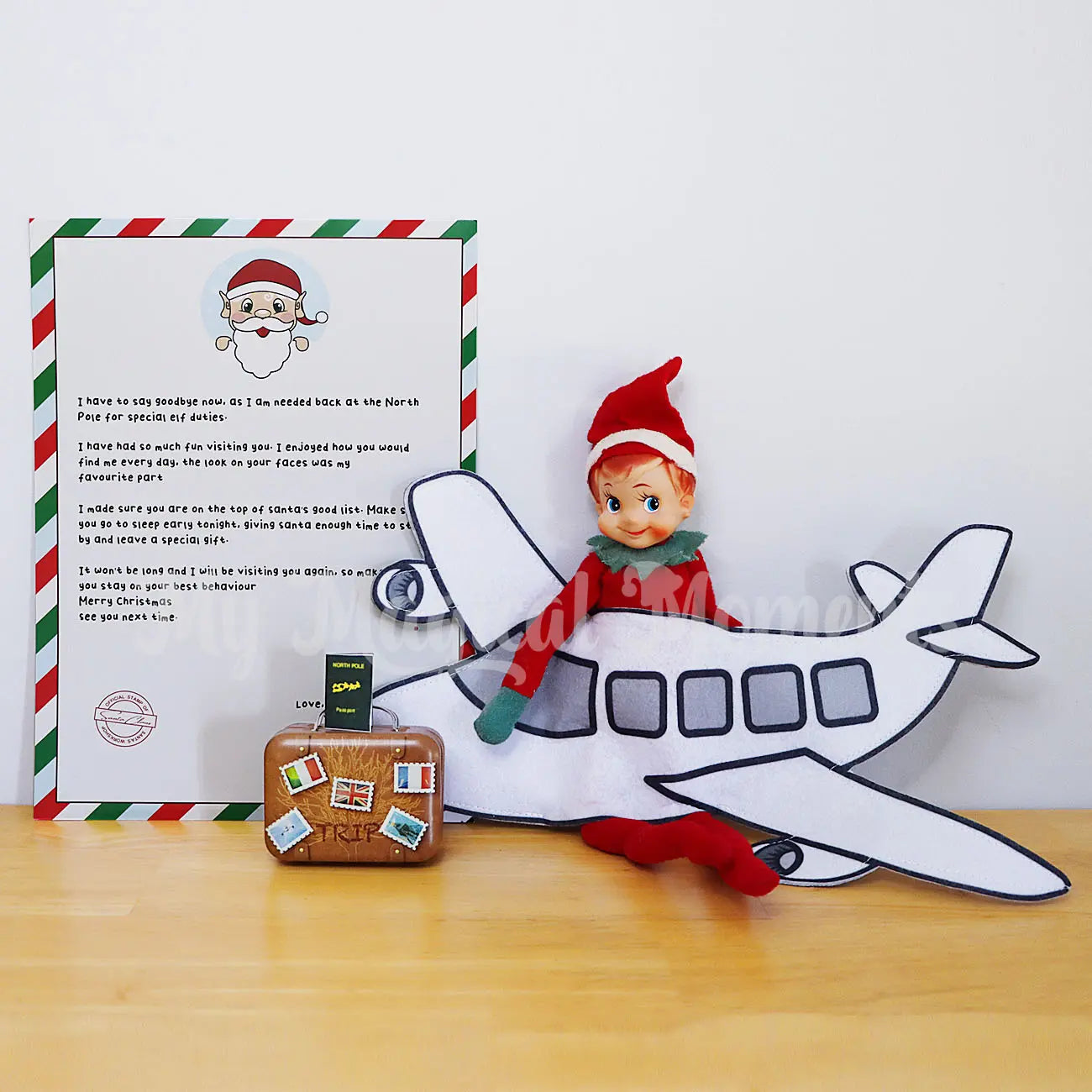 Elf wearing an airplane costume, suitcase, elf goodbye letter and mini passport