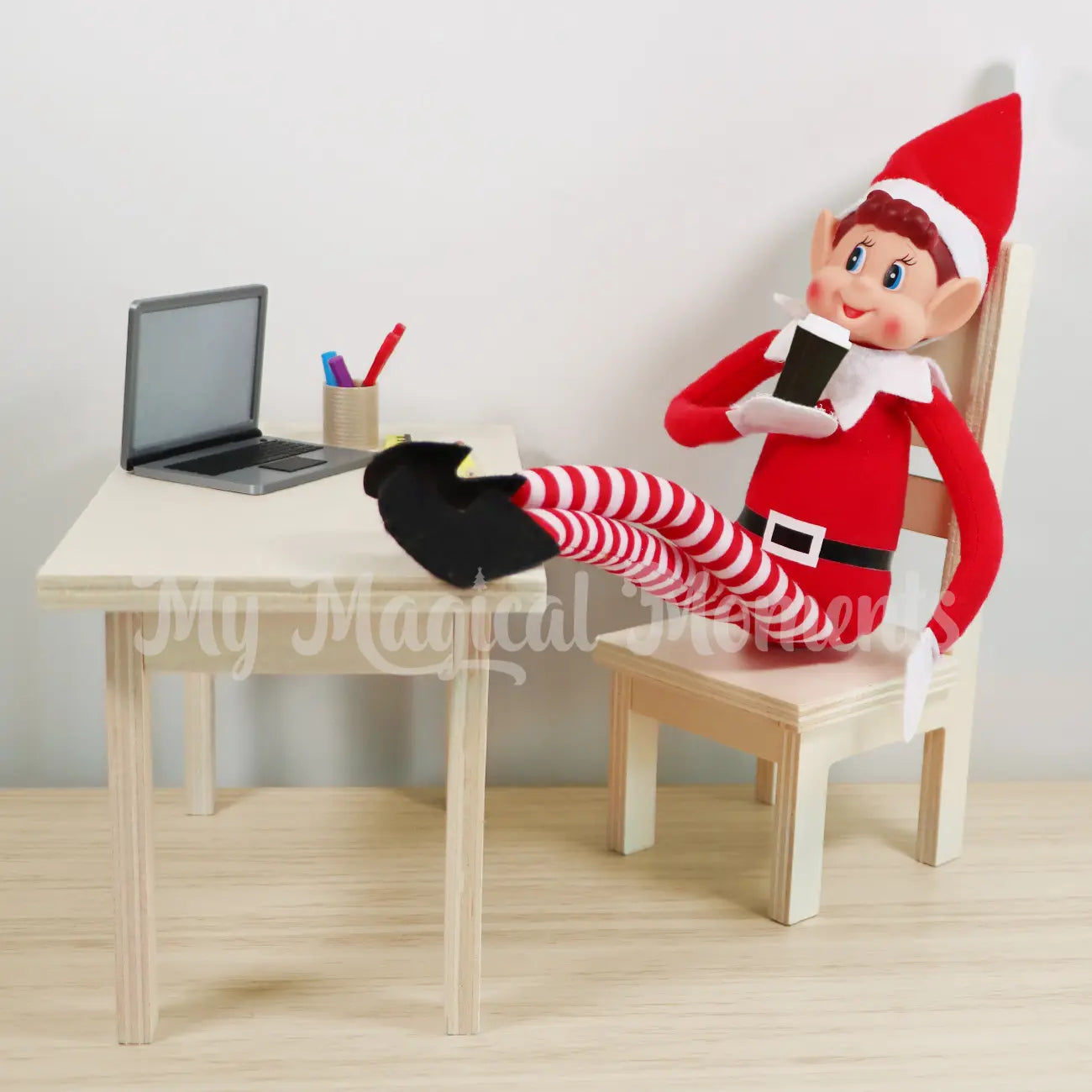 Elf drinking coffee in the office with mini laptop prop, and elf accessories, sitting on a mini wooden dining table