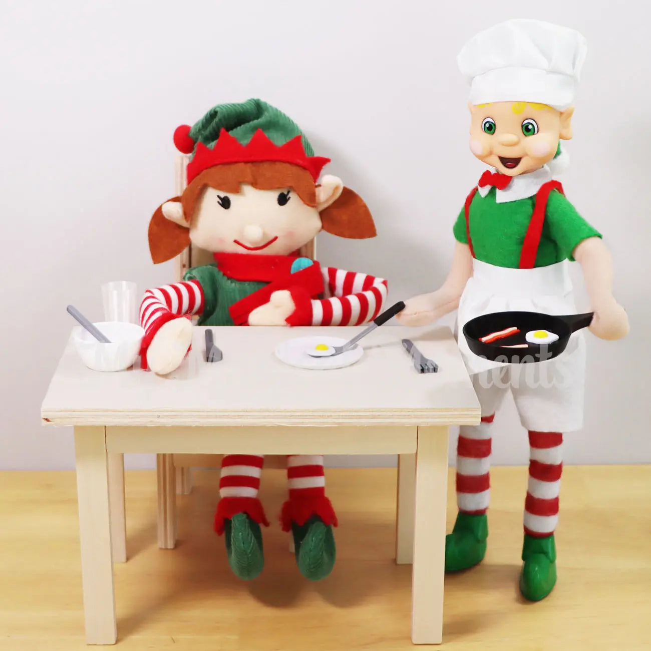 Blonde Hair My Elf Friends Elf Standing Serving bacon & Eggs in a mini elf frying pan to an elf for Christmas elf at a wooden dining table set