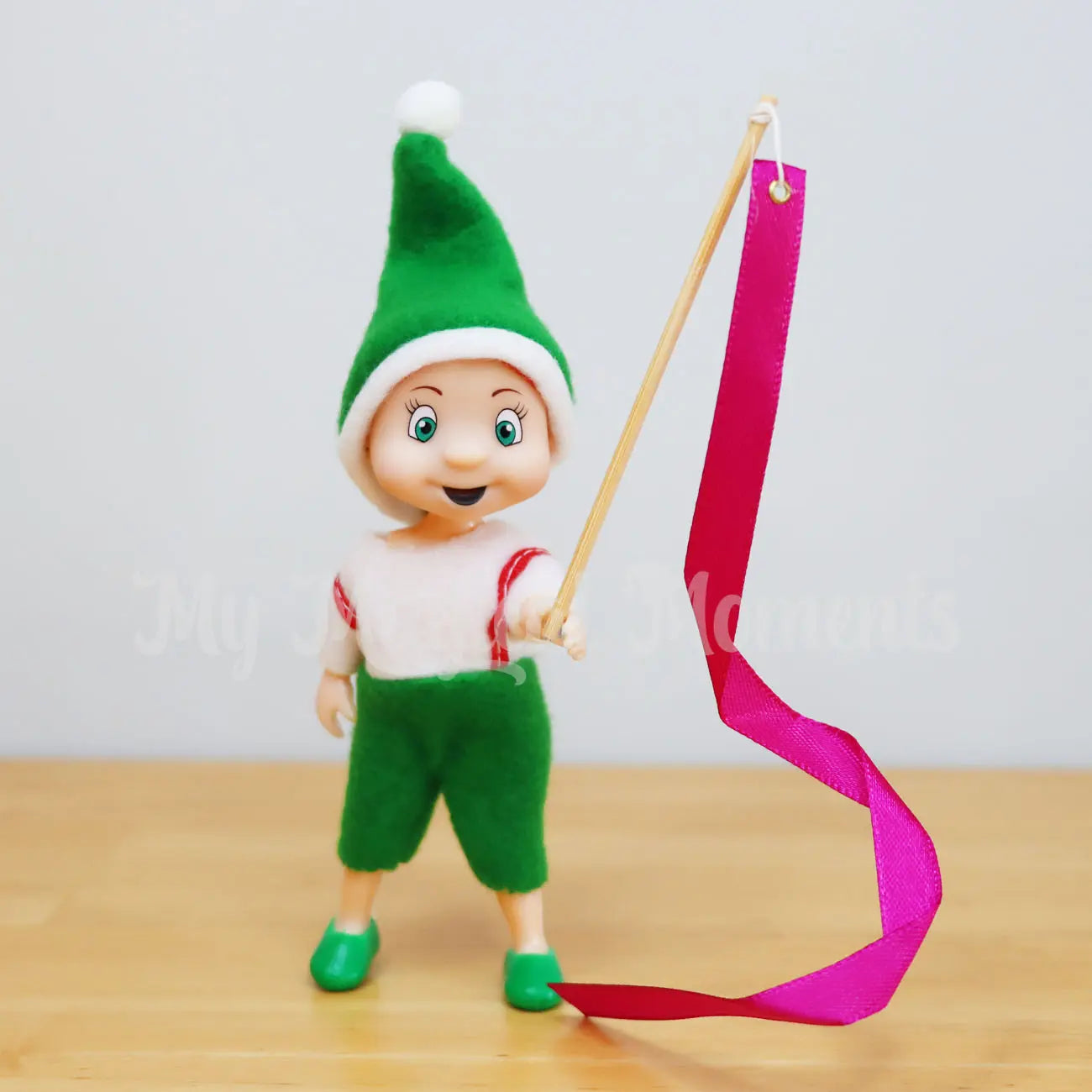 Elf toddler holding a miniature ribbon