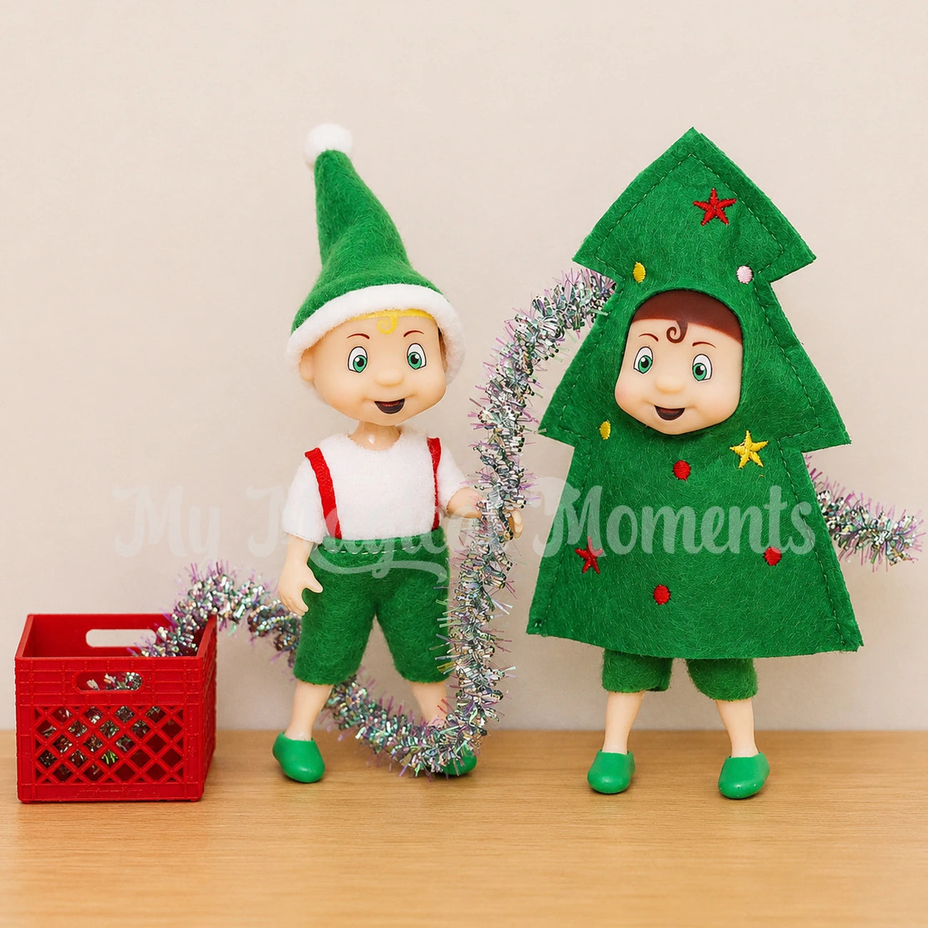 Elf toddler wearing a tree costume being decorated by a blonde hair toddler elf