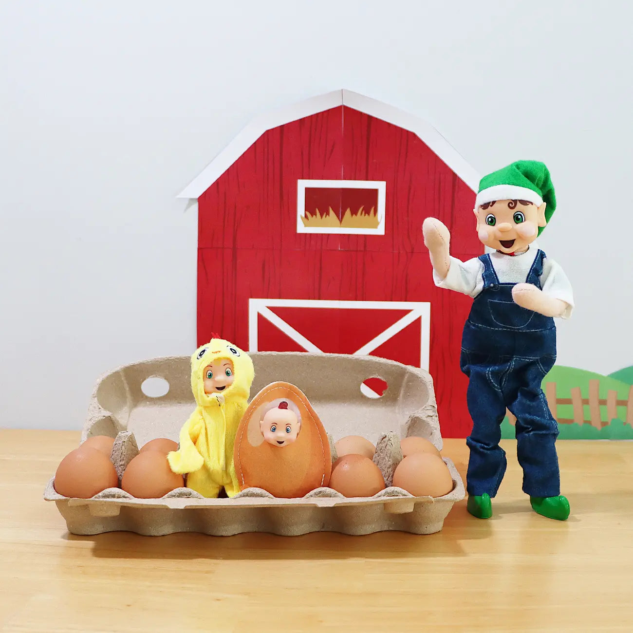 Brown Hair Elf wearing overalls counting eggs with an elf baby dressed as an egg and an elf toddler wearing a chick costume in front of a free elf printable barn