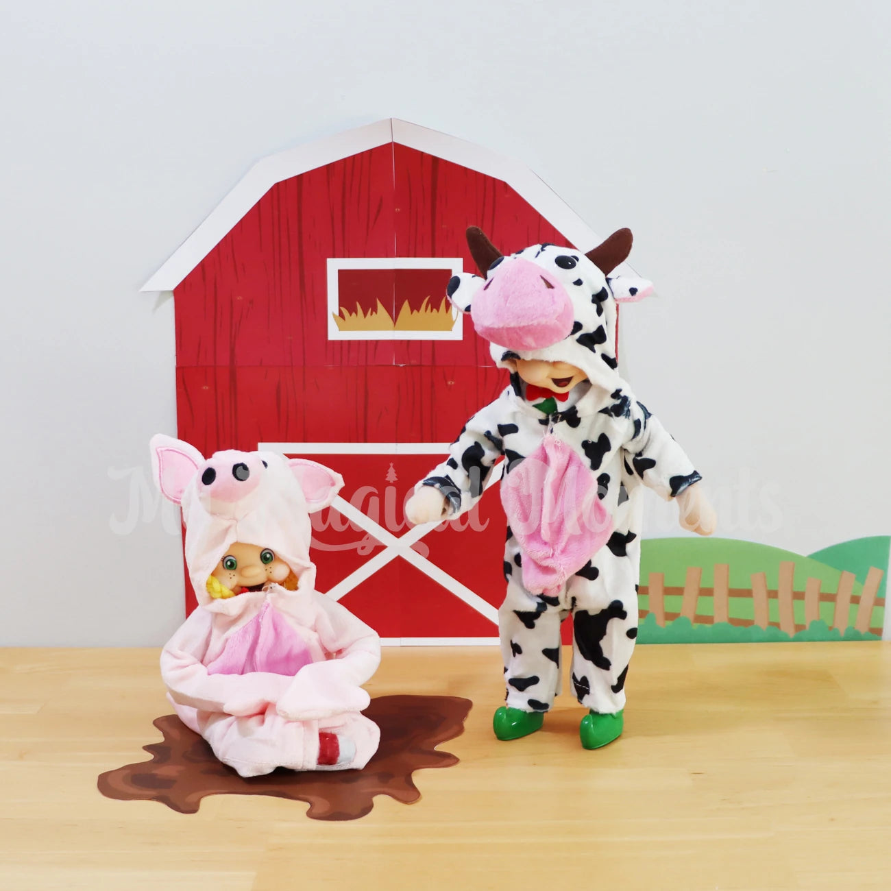 elf wearing a pig costume, sitting on a pile of mud, with an elf standing wearing a cow costume, in front of a printable barn picture