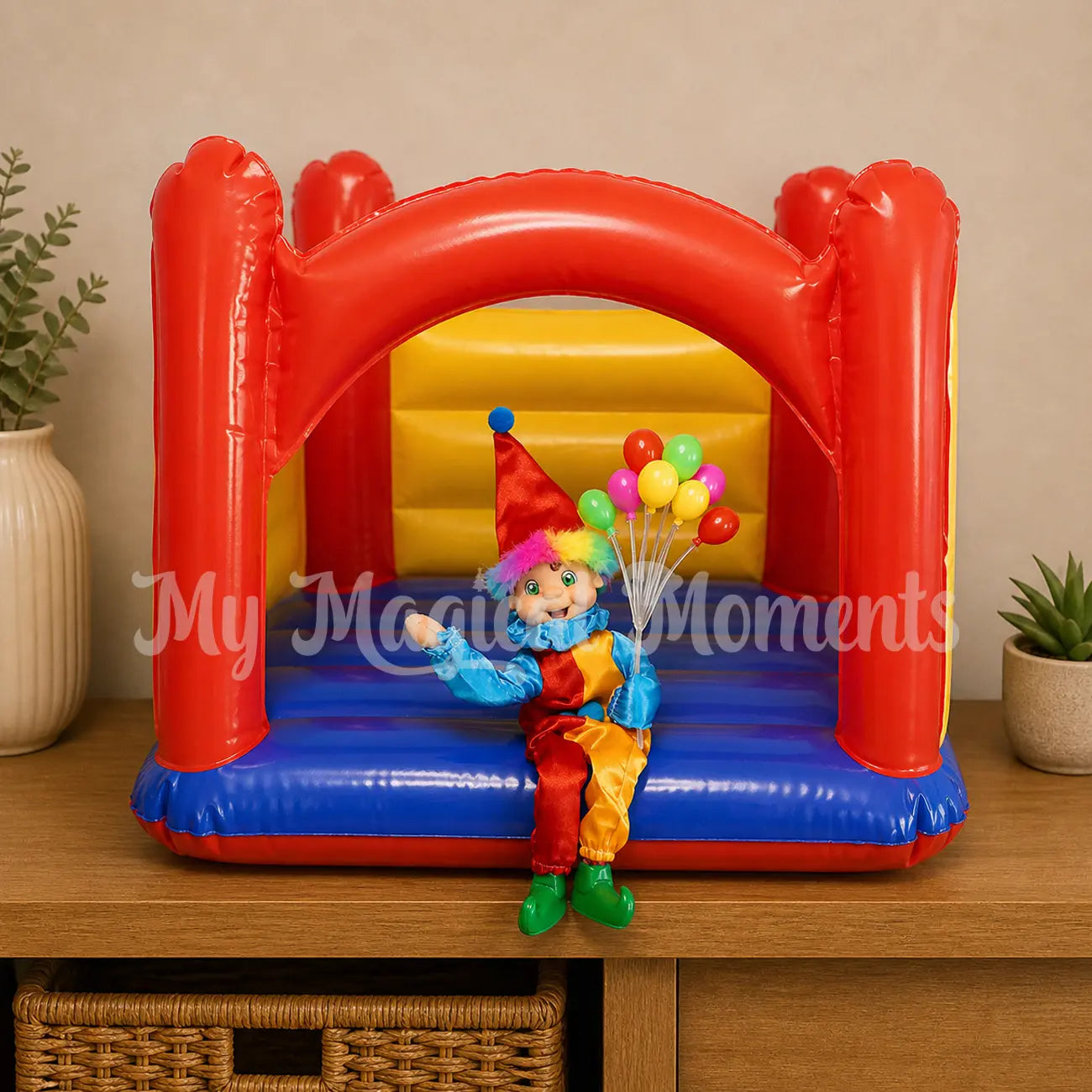Elf wearing a clown costume holding balloons on a jumping castle