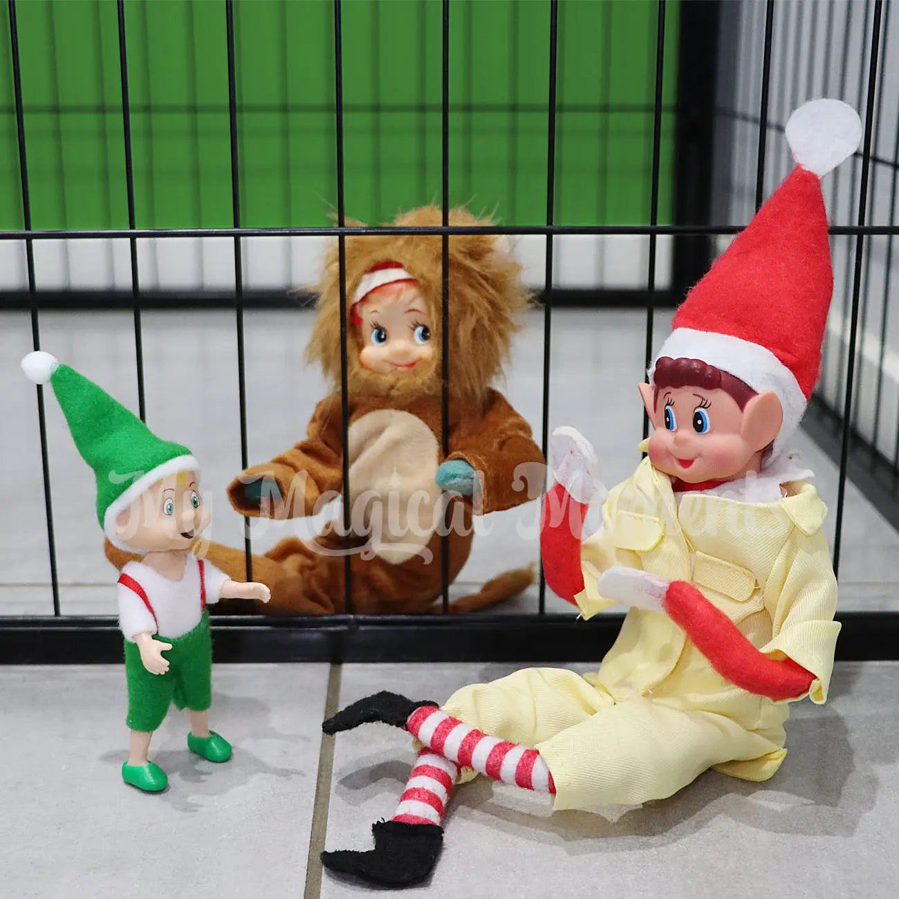 Elf dressed as a lion in a dog pen with a elf dressed as a zoologist and toddler elf