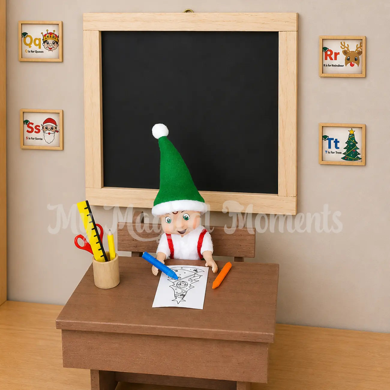Elf toddler colouring on an elf sized school desk with crayons and miniature stationery. There is a chalkboard behind