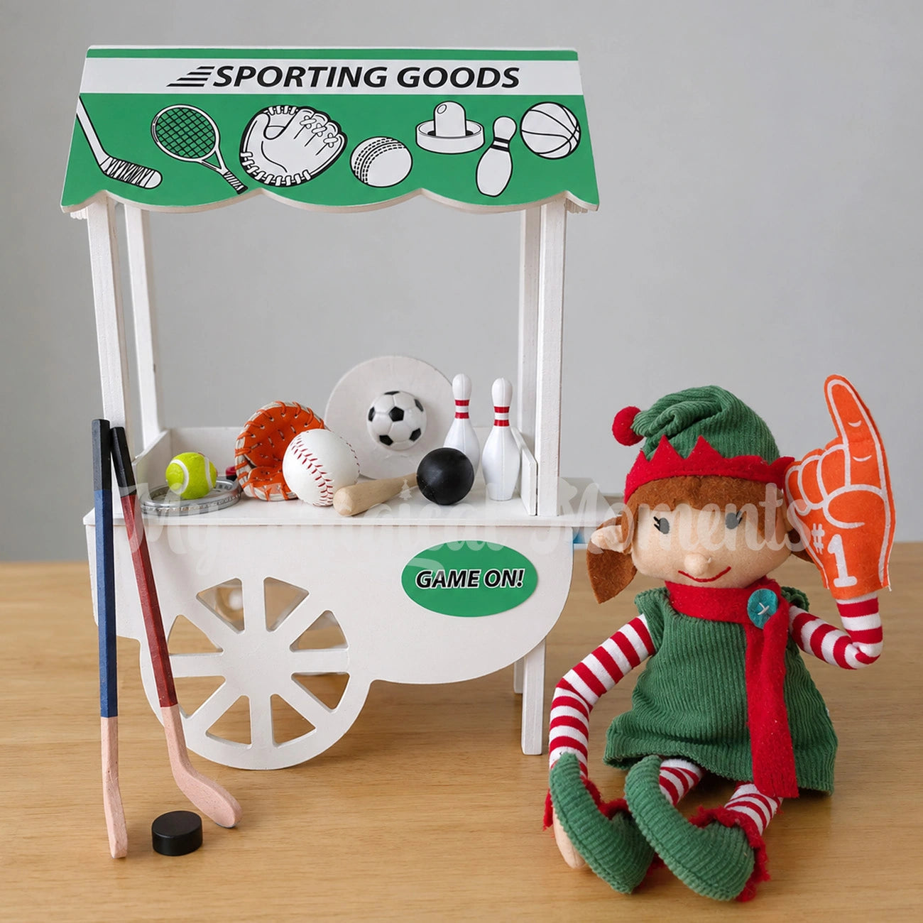 Elf wearing a #1 foam finger selling items at a sporting goods store, Mini Bowling Set, baseball , mini tennis racquet, Soccer ball, Hockey Set