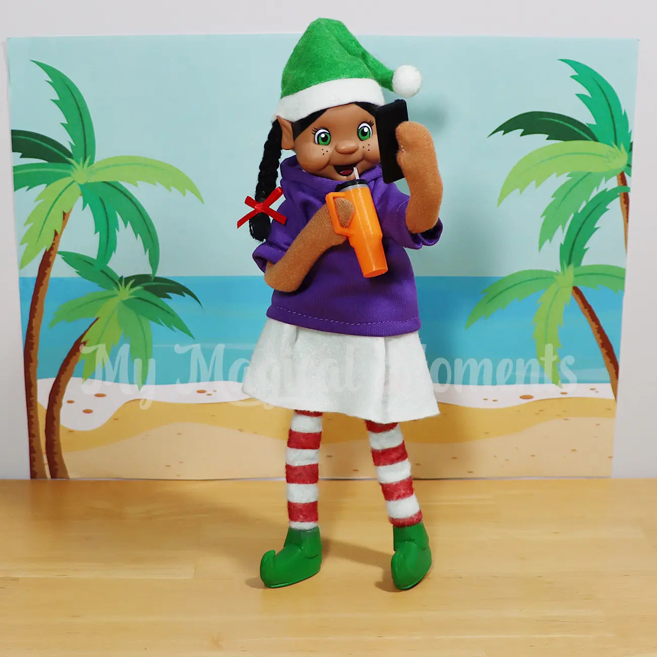 Black Hair standing Elf wearing a purple shirt taking a selfie with a mini mobile phone and with a beach background