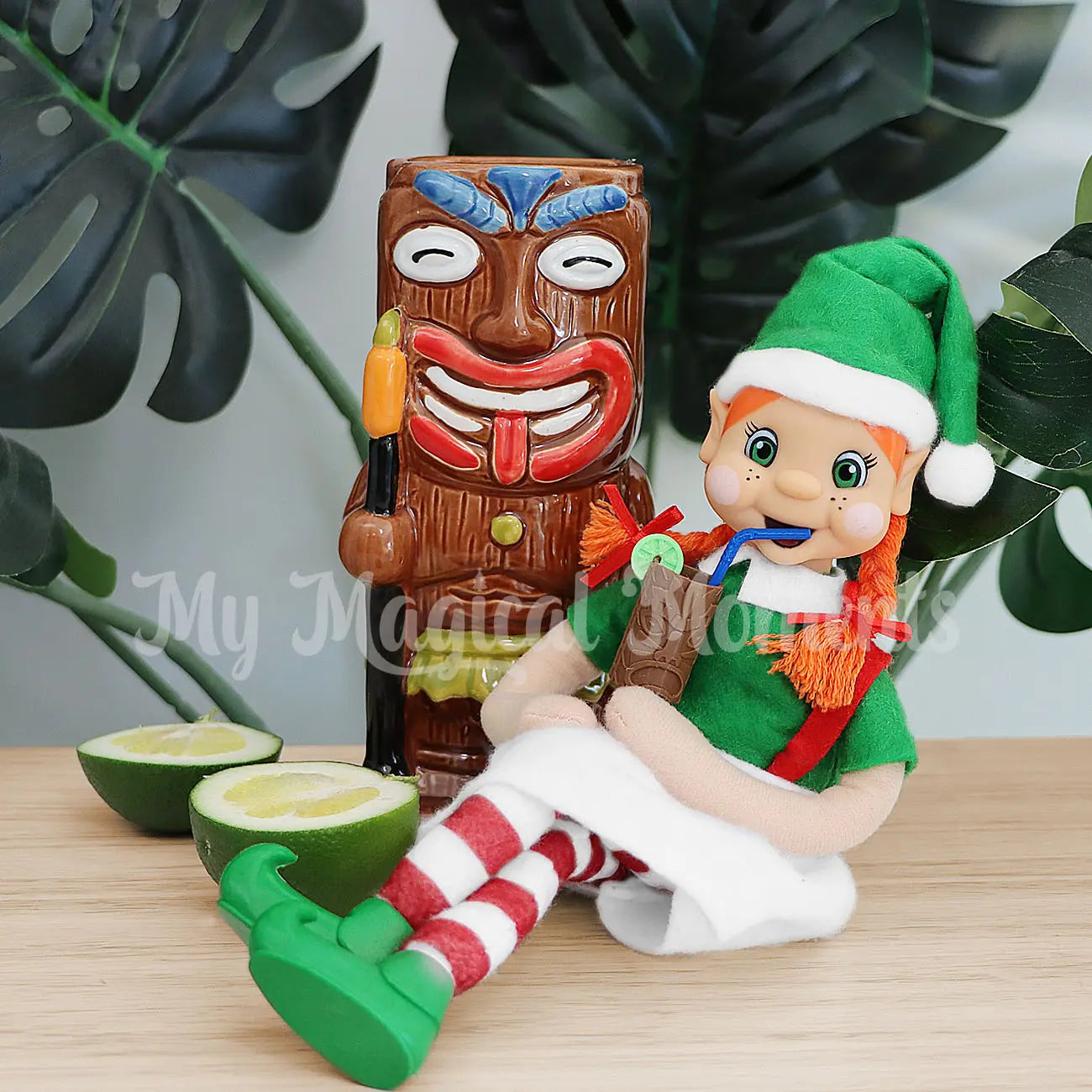 My Elf Friends Orange Hair Girl Bendable Elf drinking from a tiki cup in front of lime and a tiki cup cocktail