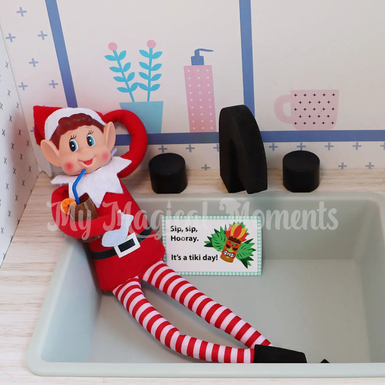 Elf drinking an elf sized tiki cup in a kids kitchen toy sink