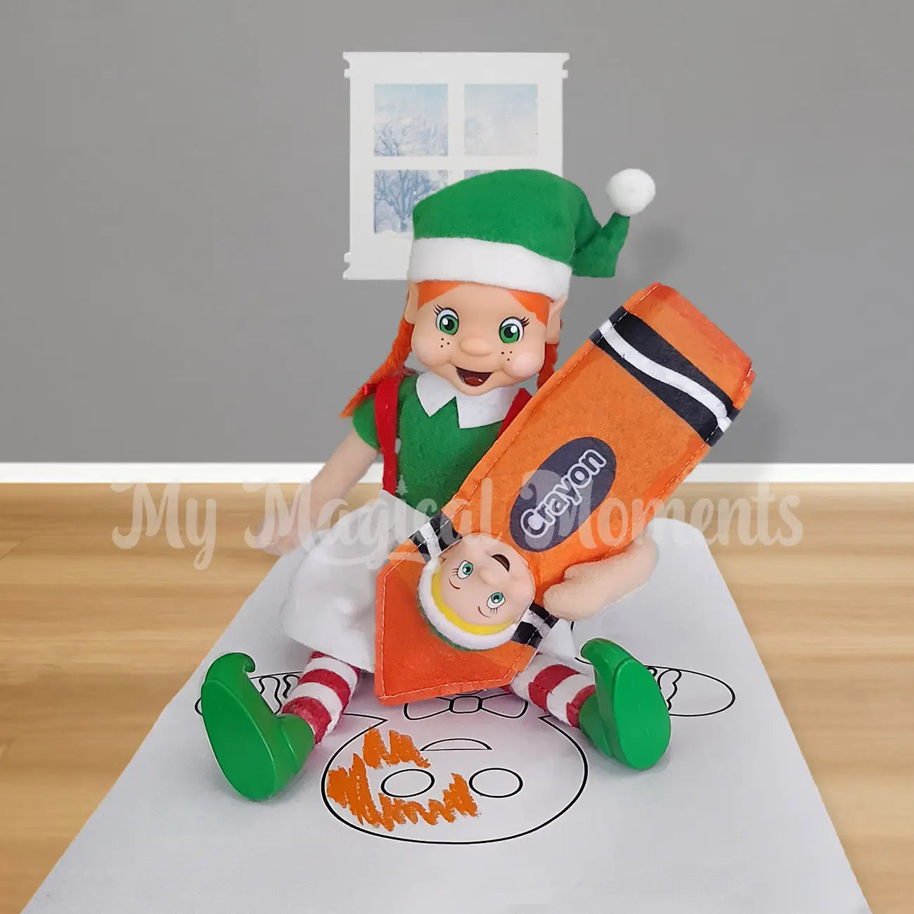 Orange hair girl elf colouring in a gingerbread with a orange crayon worn by a toddler elf