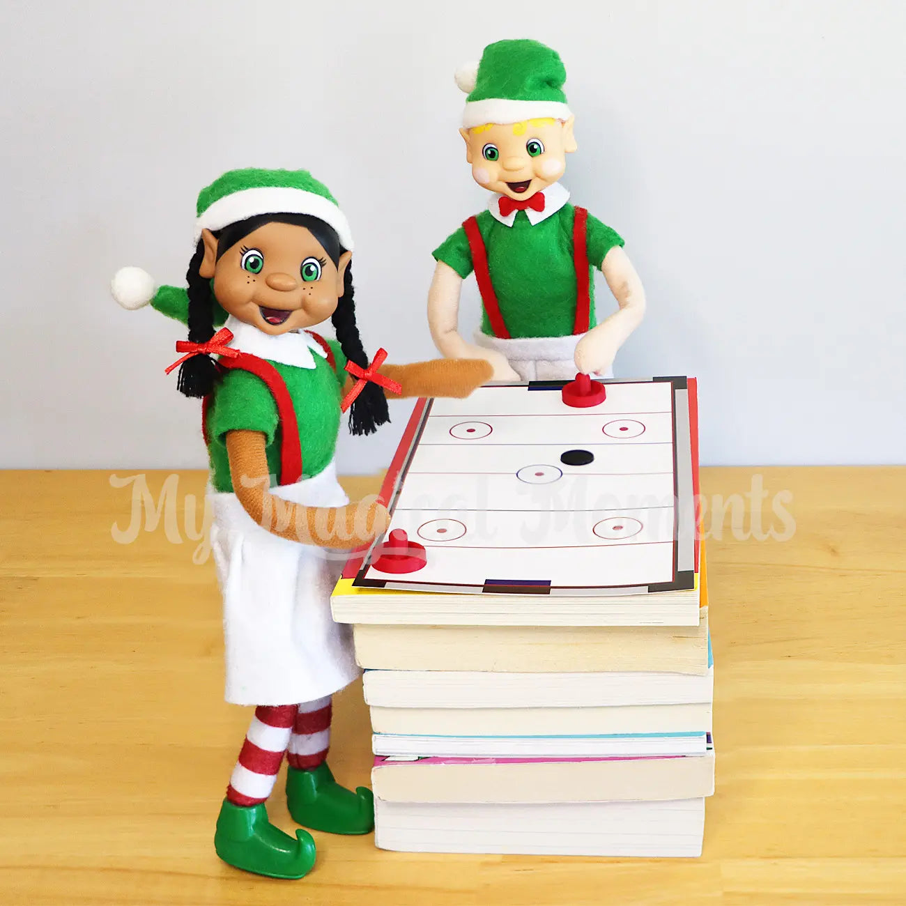 Bendable standing Elves playing air hockey on a bunch of books. 