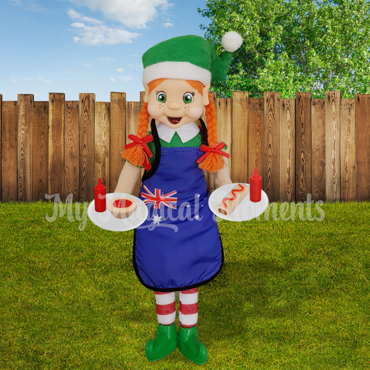 Elf wearing a bbq apron holding miniature pies and sausage rolls on a plate with tiny sauce bottles