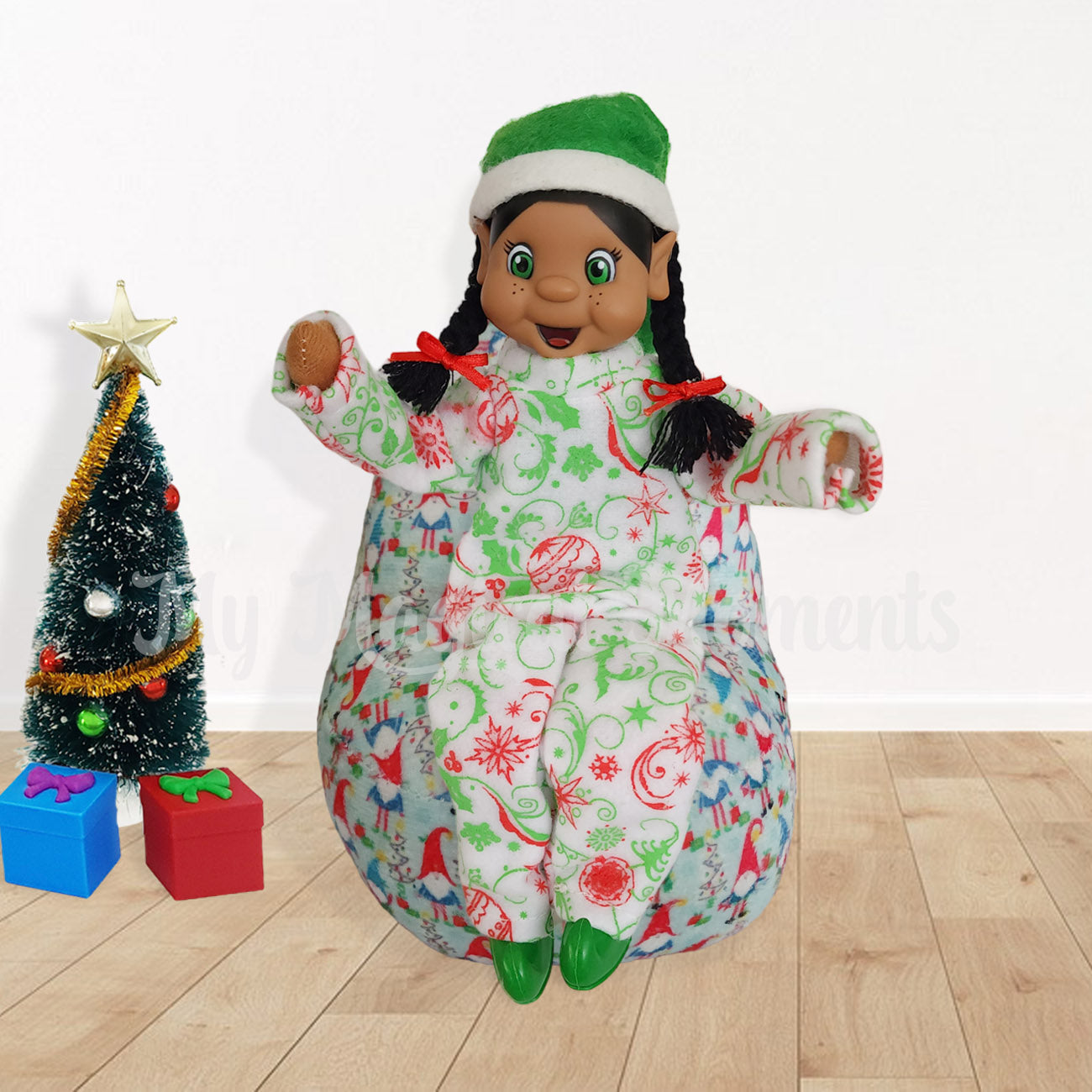 Black hair elf in pyjamas sitting on a bean bag with a Christmas tree