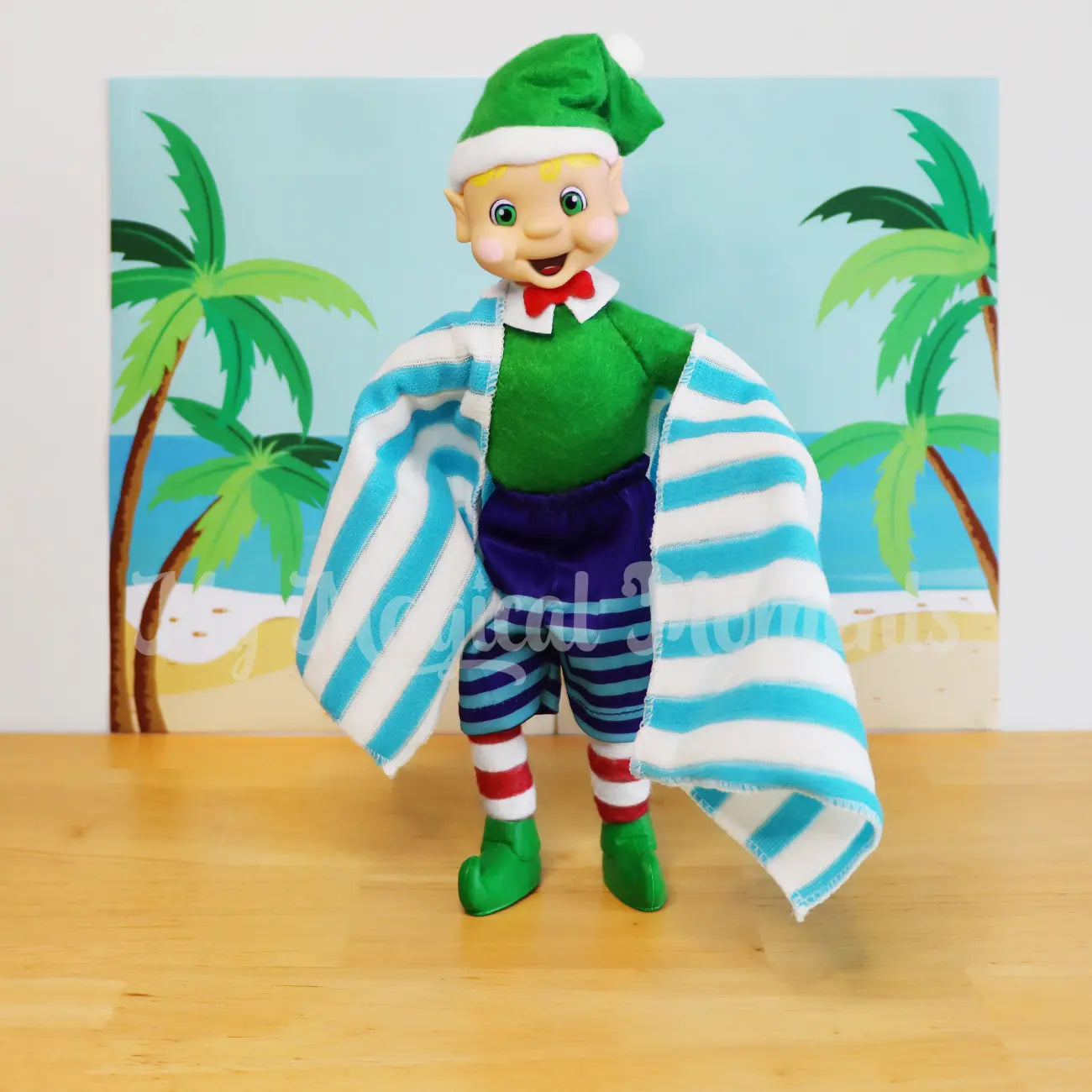 elf wearing mini boardies holding a elf sized beach towel