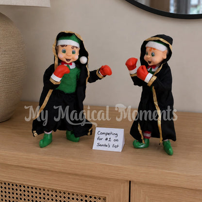 Elves Wearing boxing outfits, with boxing gloves having a boxing match on the table with a note saying competing for  #1 on Santa's List