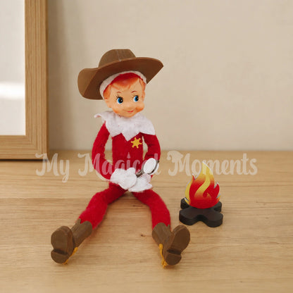 An elf wearing a cowboy hat and boots holding a toasting marshmallow over a fire pit