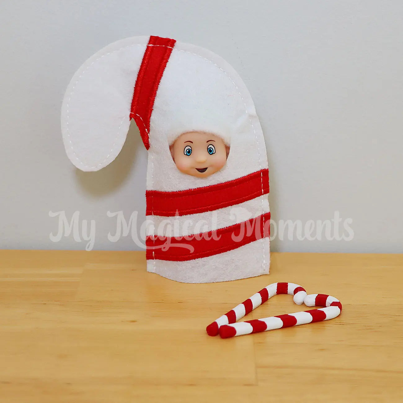 Elf baby wearing a candy cane costume with mini candy cane elf props