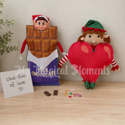 Elves behavin badly elf wearing a chocolate bar costume with a second elf An Elf for Christmas dressed as heart costume with mini chocolate and lollies
