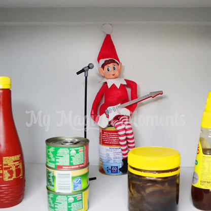 Elf playing a mini electric guitar prop singing into a mini elf microphone to condiments