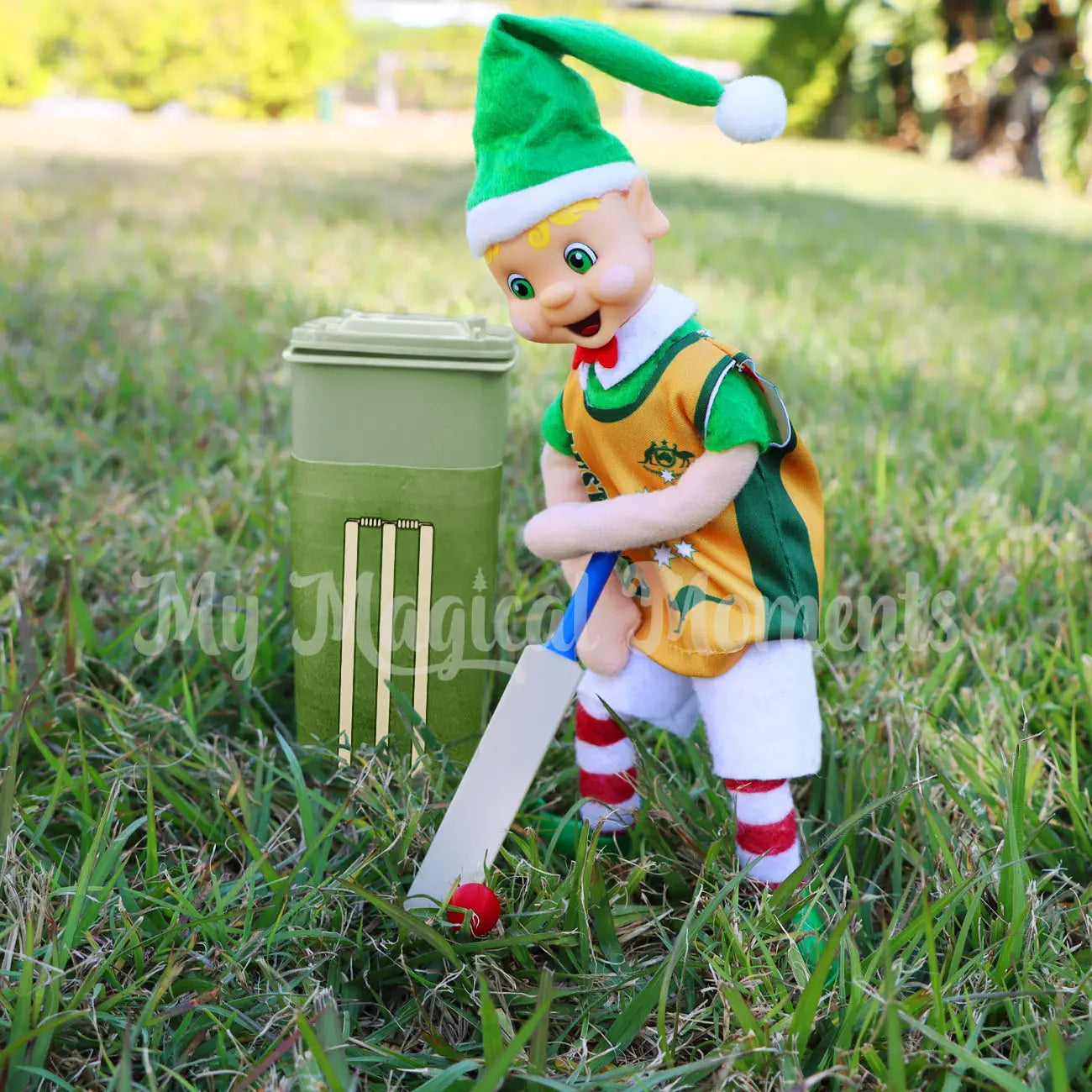 Elf playing Cricket with a mini cricket bat, ball and elf sized bin. Wearing an aussie singlet