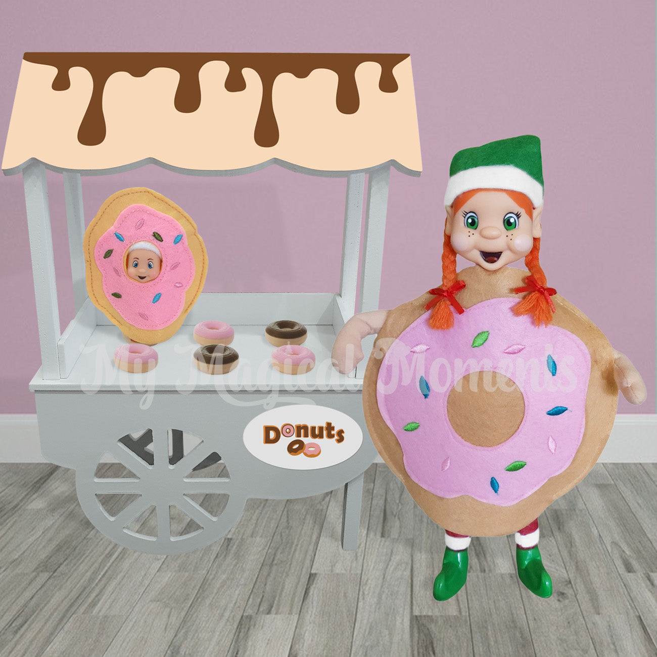 Elf dressed as a donut standing in front of a doughnut store with a baby elf dressed as a donut