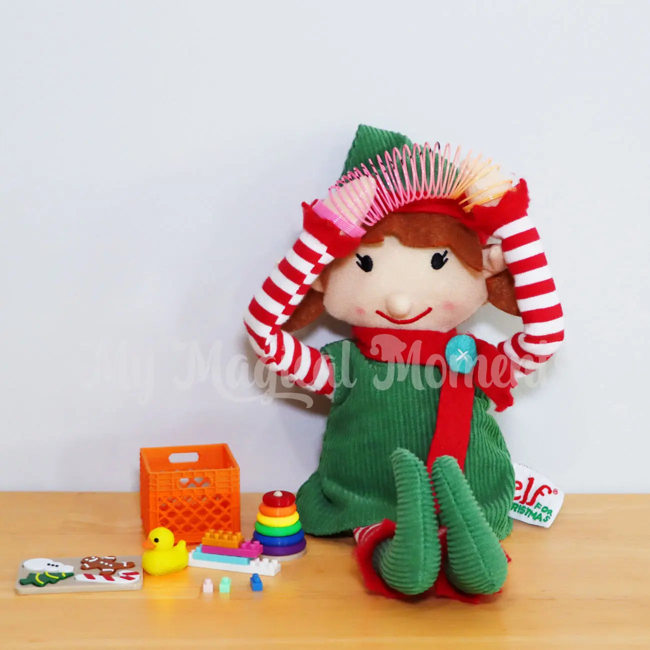 Elf playing with a mini slinky and other elf toys, mini lego, rubber ducky, puzzle, ring toss and mini crate