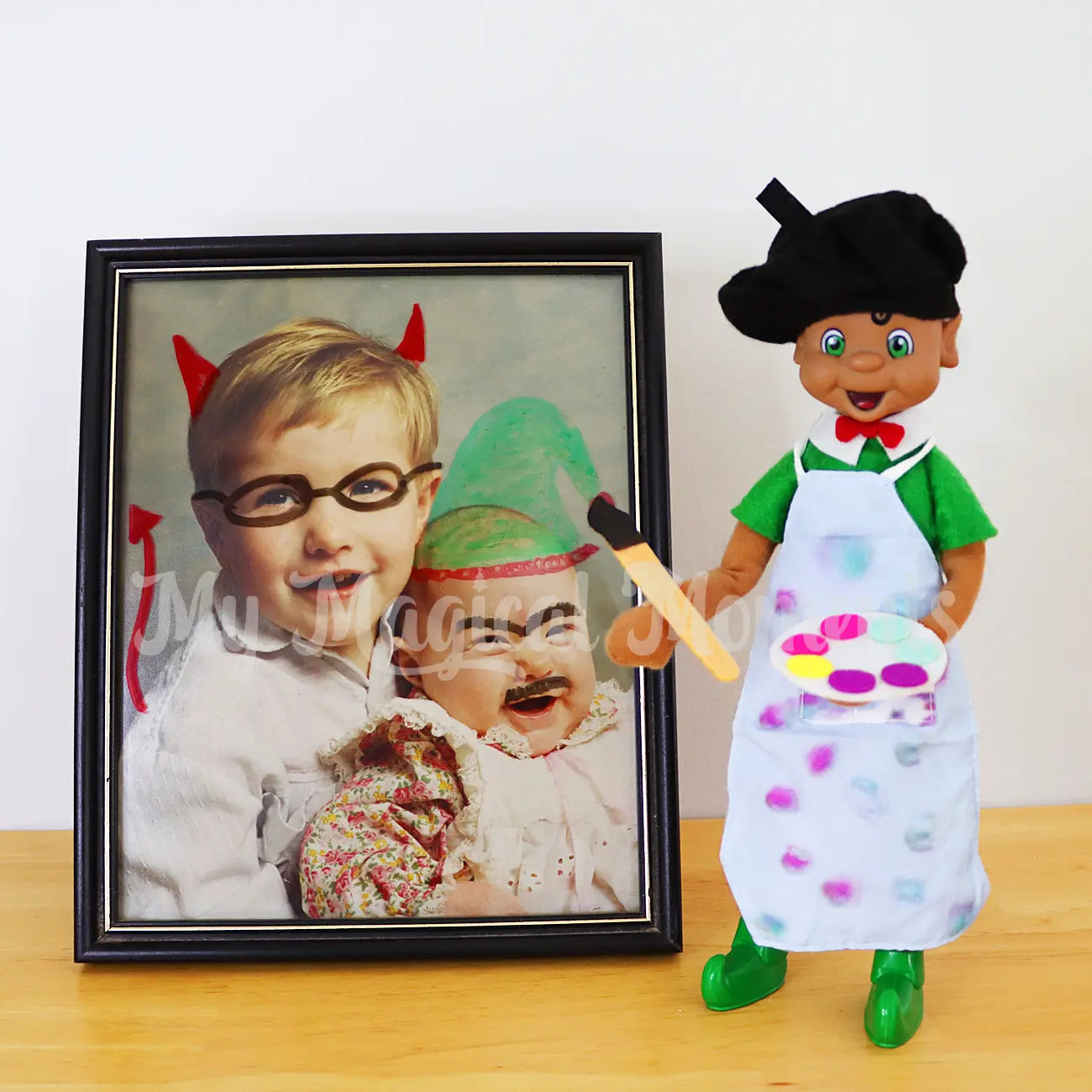 elf wearing an artist frock, holding a mini paintbrush drawing on photos