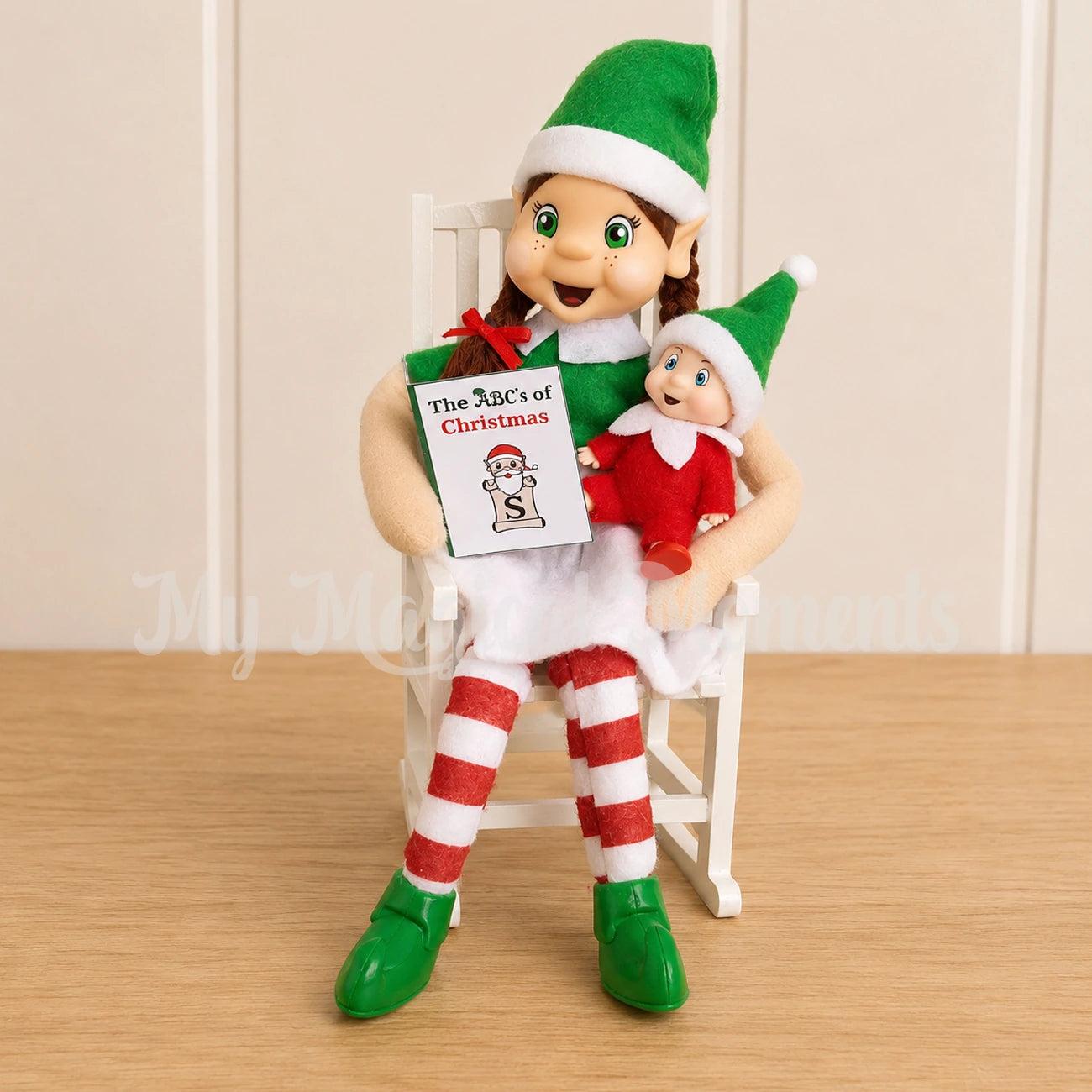 A brown hair girl elf reading a story to a baby elf in a rocking chair