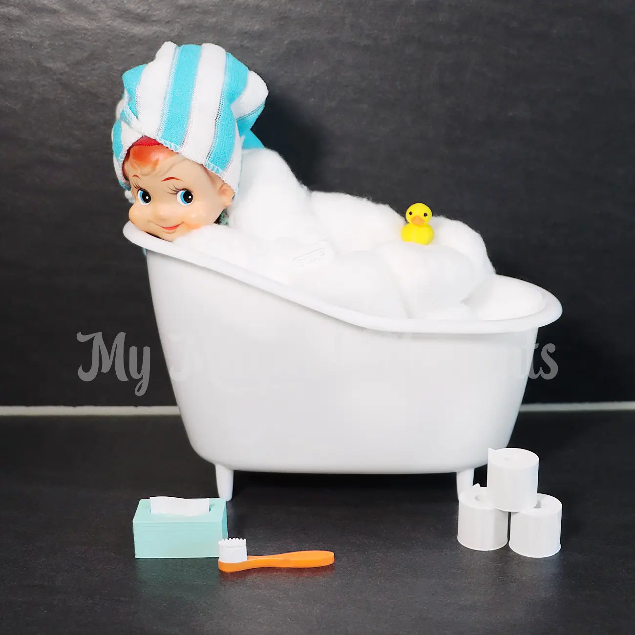Vintage Elf Shelf in bath with rubber ducky, bath towel and a bathroom set containing mini tooth brush, tissue box and toilet paper