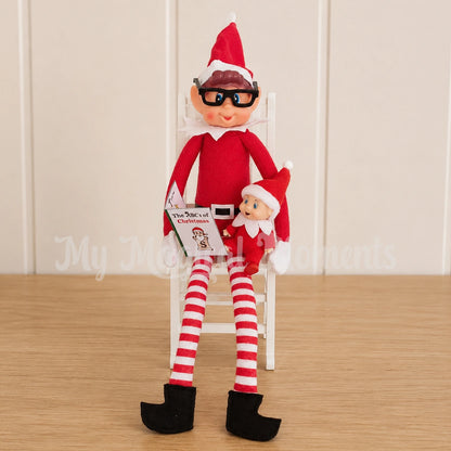 an elves behavin badly elf wearing glasses reading a story to an elf baby