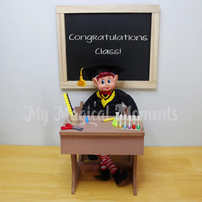 Elf wearing a graduation outfit graduating end of class in his little desk