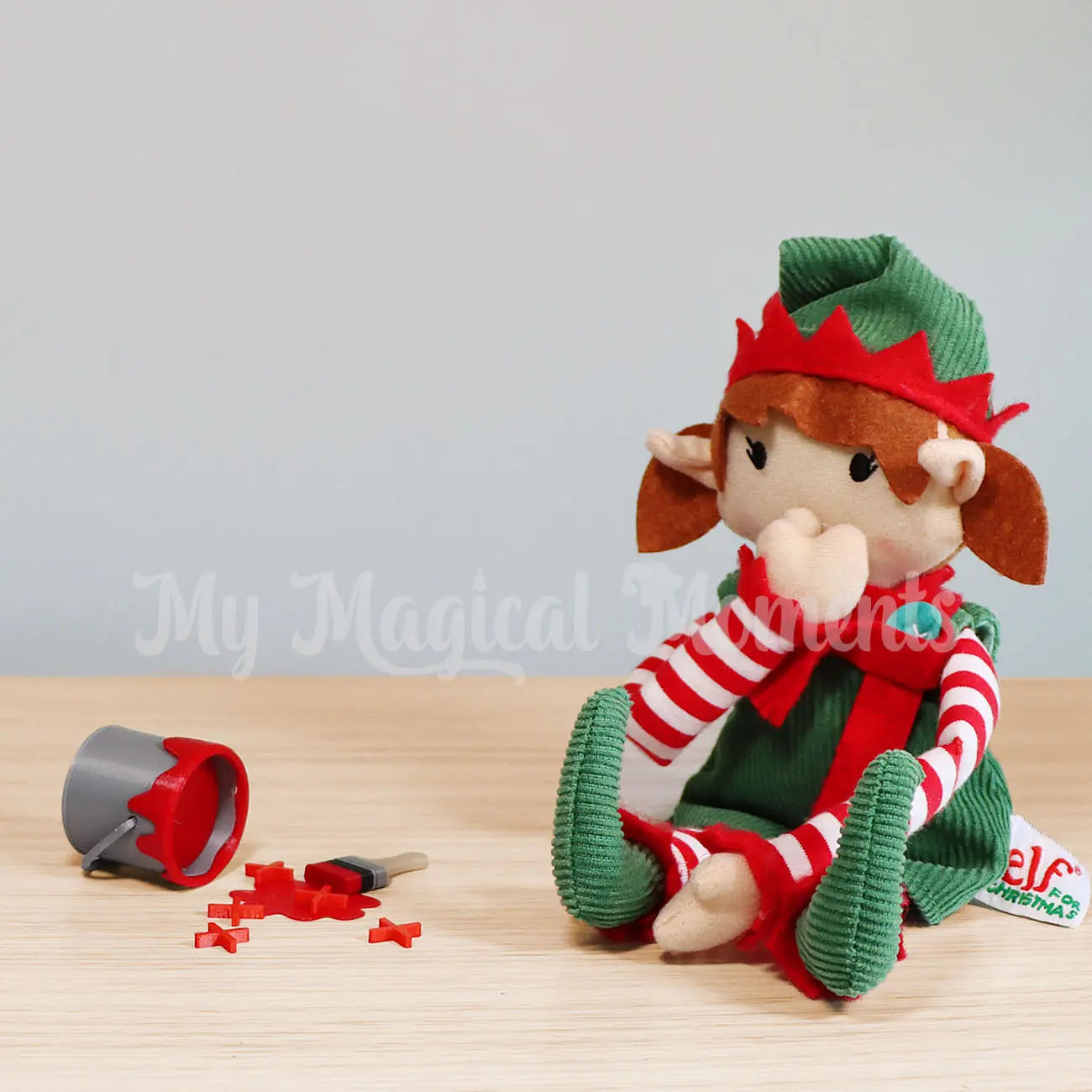 An Elf For Christmas doll painting Xs with an elf sized red paint tin