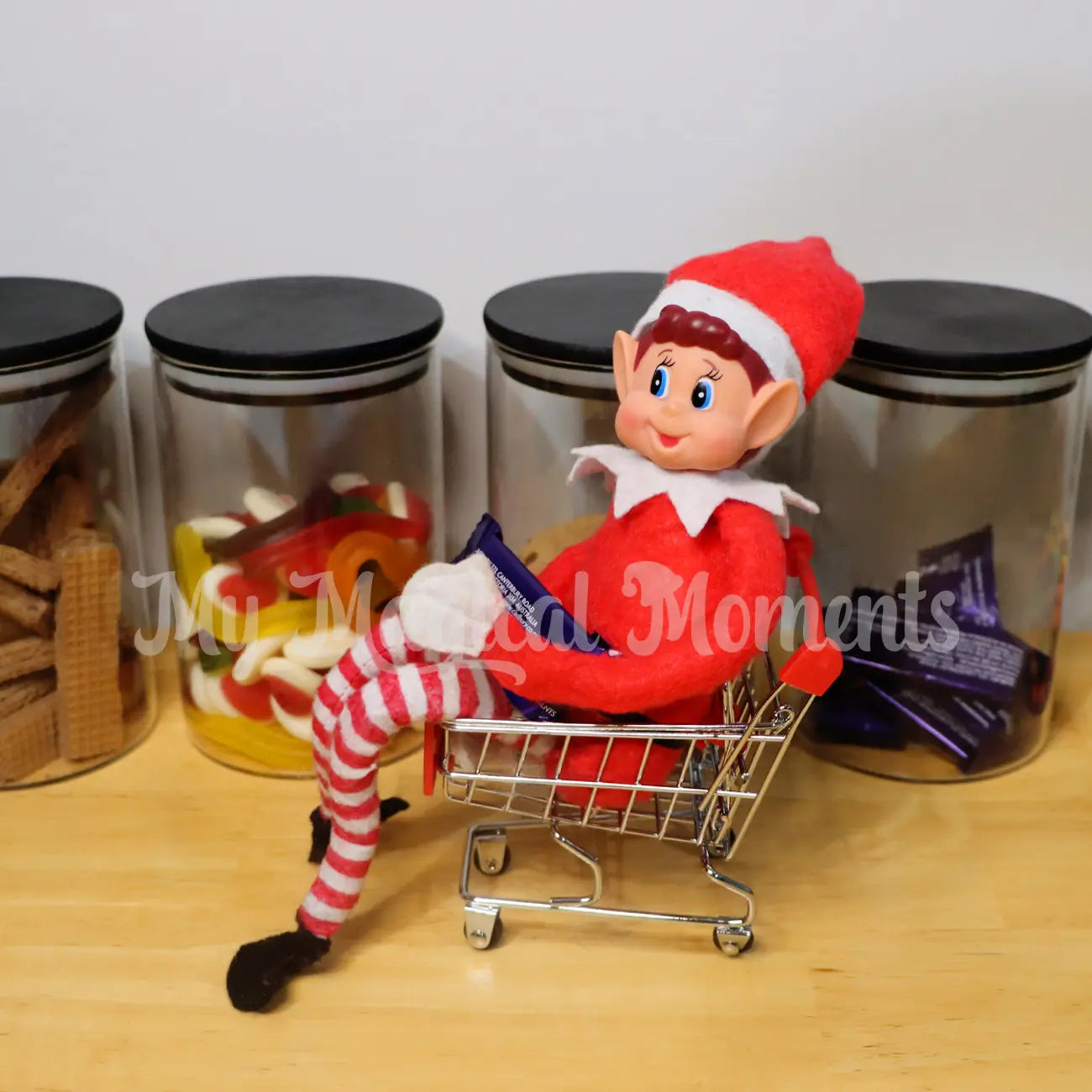 Elf sitting in a mini shopping trolley with food