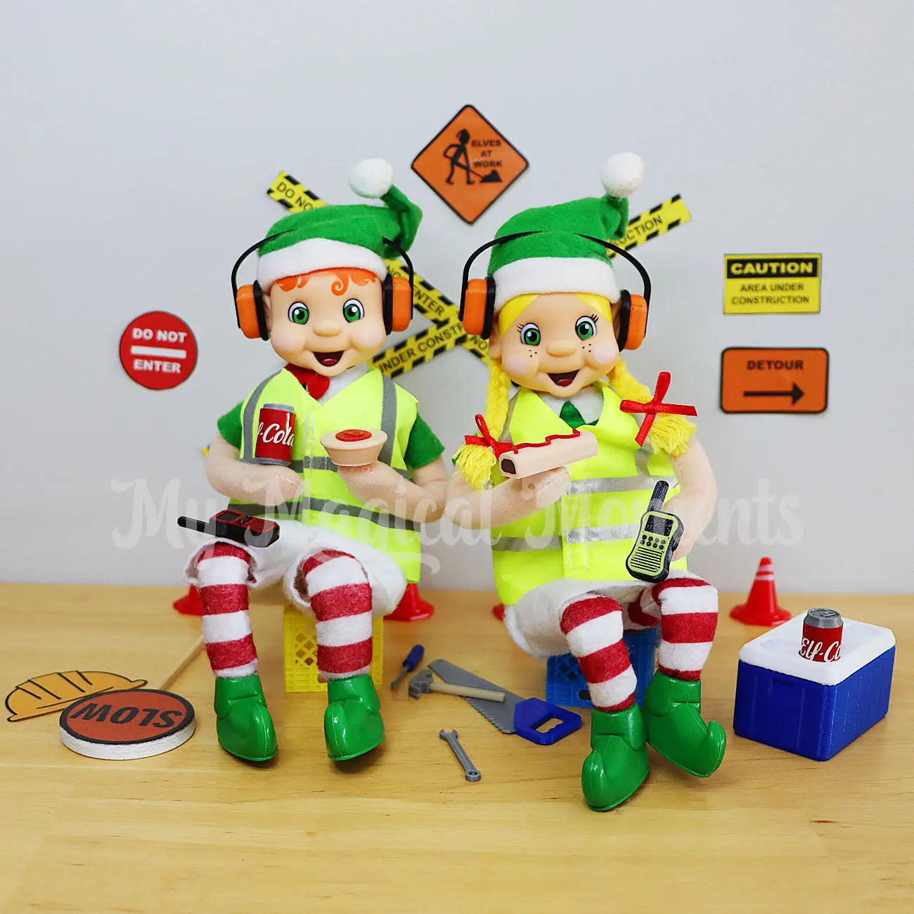 Elves dressed as tradies wearing headphones with pies & sausage rolls on a smoke-o at a construction site