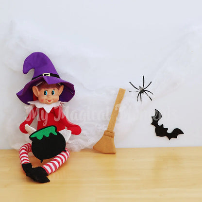 Elf wearing a witches hat holding a cauldron with broomstick, cobwebs and bat