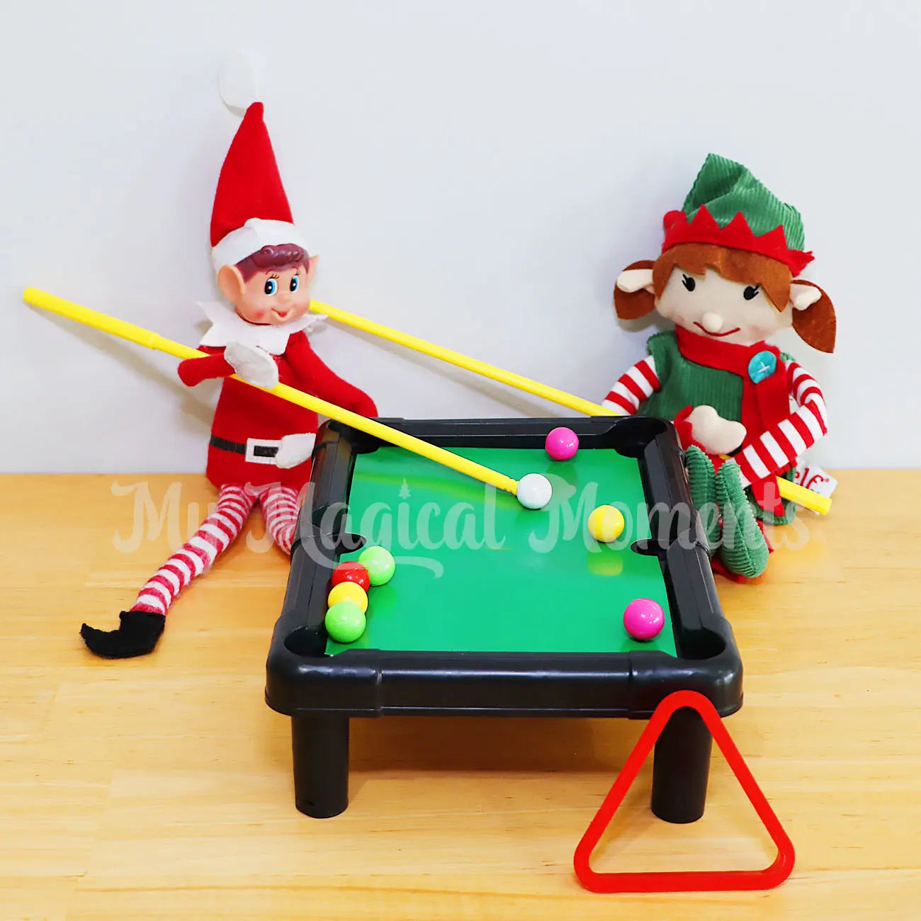 Elves playing on billiard table with mini balls, triangle and pool cues