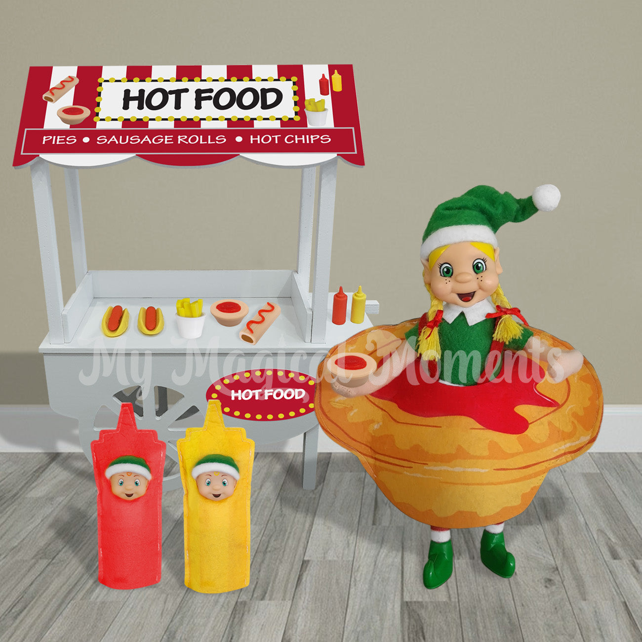 Elf scene hot food cart selling hot dogs, pies and hot chips. With an elf dressed as a pie holding a mini pie with sauce. Two toddlers are dressed as condiments